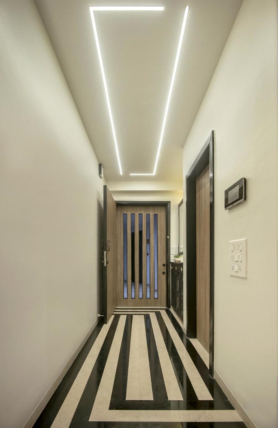 The entryway makes an impact with its high-contrast, black and white flooring. The Art Deco-inspired pattern echoes in the recessed ceiling lighting.