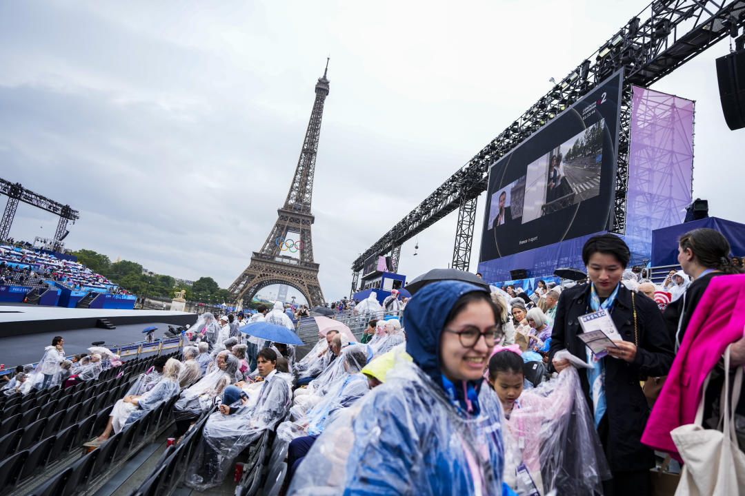 PARIS, FRANCE - JULY 26: Spectators waiting to watch the opening ceremony of the 2024 Paris Olympics try to shield themselves from the rain in Paris, France on July 26, 2024. (Photo by Mustafa Ciftci/Anadolu via Getty Images)