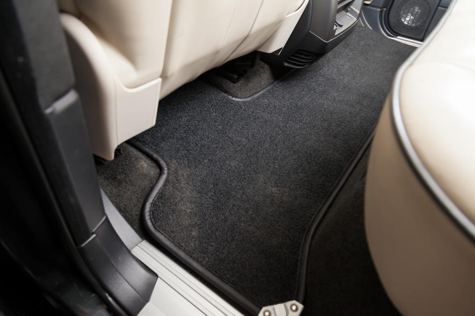 Clean car floor mats of black carpet under rear passenger seat in the workshop for the detailing vehicle before dry cleaning. Auto service industry. Interior of sedan.