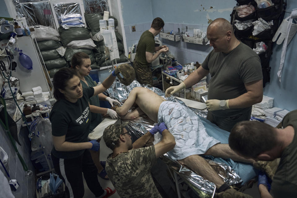 Military medics give first aid to a wounded Ukrainian soldier at a medical stabilisation point near Bakhmut, Donetsk region, Ukraine, Monday, June 19, 2023. (AP Photo/Libkos)