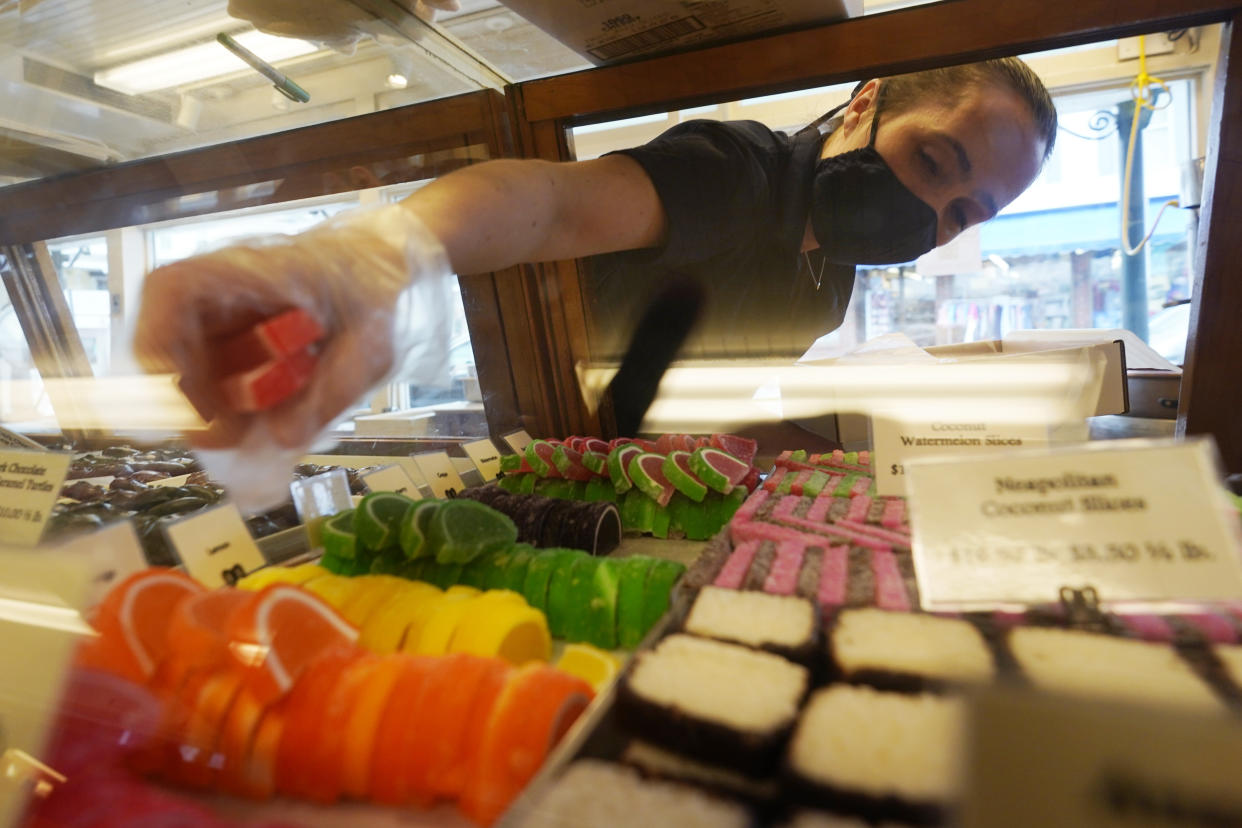 Beth Duckworth fills a display cabinet with sweet treats at The Goldenrod, a popular restaurant and candy shop, Wednesday, June 1, 2022, in York Beach, Maine. The business is looking to hire 30 to 40 more workers in addition to the 70 or so it now employs. (AP Photo/Robert F. Bukaty)