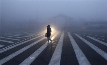 A woman walks along a street during a smoggy day in Changchun, Jilin province, October 22, 2013. REUTERS/China Daily