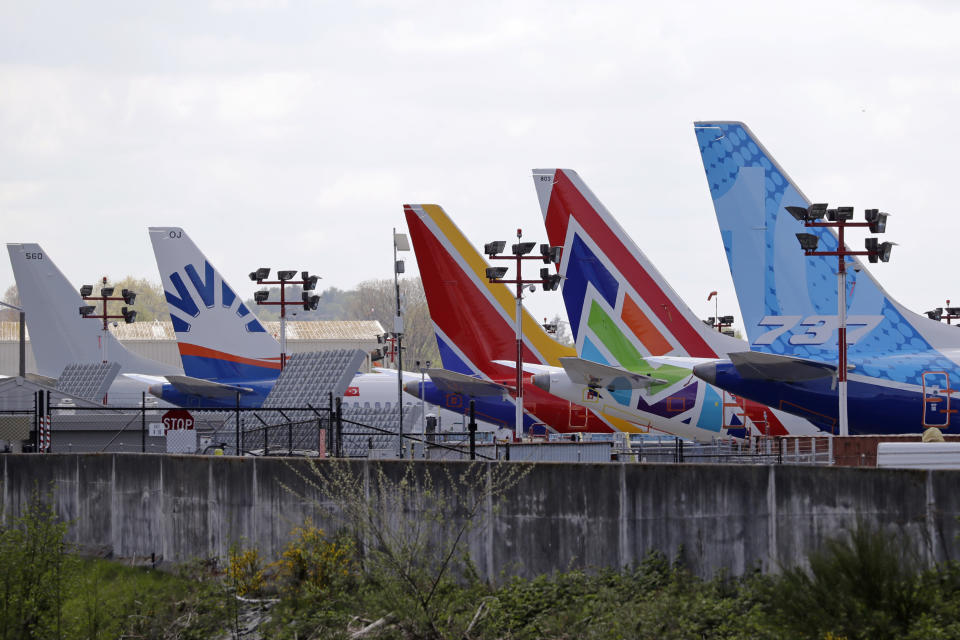 A line of Boeing 737 MAX jets sit parked on the airfield adjacent to a Boeing production plant Monday, April 20, 2020, in Renton, Wash. Boeing this week is restarting production of commercial airplanes in the Seattle area, putting about 27,000 people back to work after operations were halted because of the coronavirus. (AP Photo/Elaine Thompson)