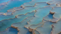 <p> Pamukkale means &#x201C;cotton castle.&#x201D; Hot water flows down from a cliff-top spring 655 feet (200 meters) from the ground. The water comes out warm when it originates from a spring 1,050 feet (320 meters) underground.&#xA0; </p> <p> As water leaves the spring it makes contact with the air for the first time and begins to change. Initially, it&#x2019;s fully saturated with minerals, but a&#xA0;chemical reaction&#xA0;causes it to release carbon. As this process happens it leaves a coating of crystals behind. Pamukkale boasts petrified waterfalls, mineral forests and terraced basins, according to&#xA0;UNESCO.&#xA0; </p>