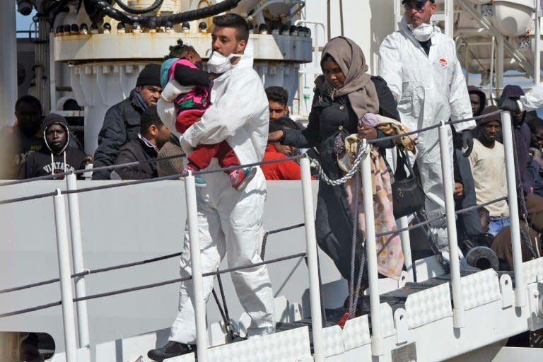 A rescuer carries a baby as migrants and refugees arrive in the port of Messina following a rescue operation on March 17, 2016 in Sicily