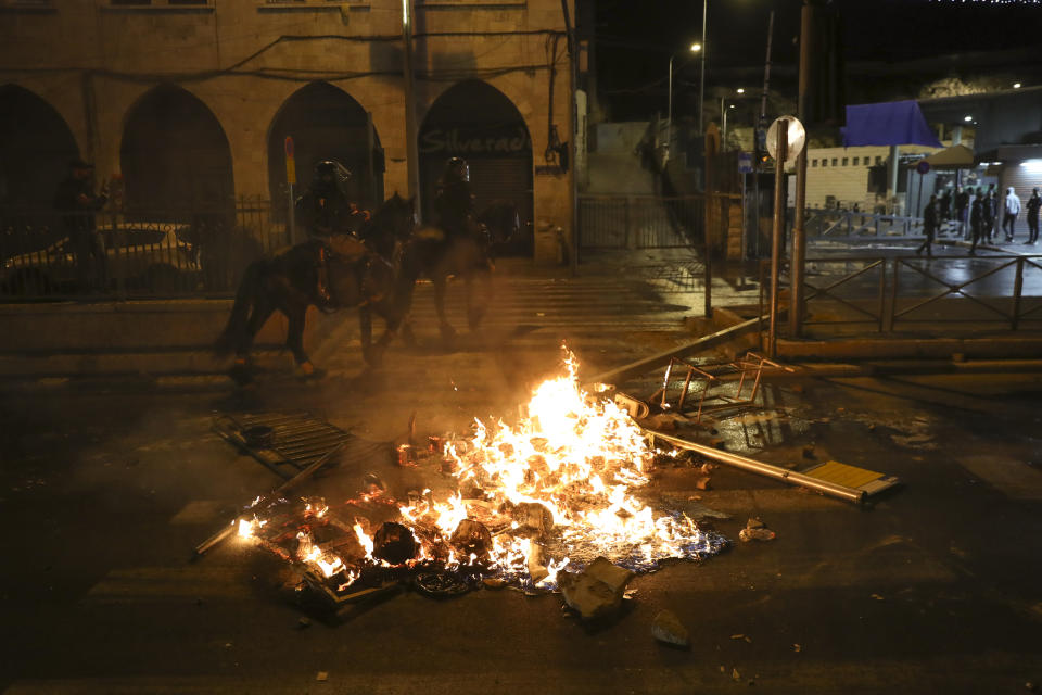 Mounted Israeli police officers ride past a fire during clashes with Palestinians, just outside Jerusalem's Old City, Thursday, April 22, 2021. Israeli police manned barricades to prevent hundreds of Jewish extremists from marching to the area as police clashed with Palestinians on a nightly basis since the start of the Muslim holy month of Ramadan last week, when they set up barricades at Damascus Gate, a traditional outdoor gathering spot. (AP Photo/Ariel Schalit)