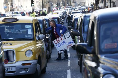 A London cab driver holds a placard during a protest by London cab drivers against Uber in central London, Britain February 10, 2016. REUTERS/Stefan Wermuth