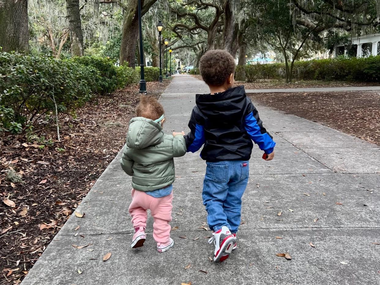 Stephanie Claytor's kids holding hands and walking on a sidewalk.