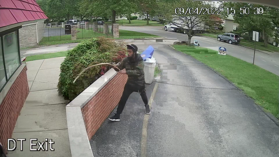 A screenshot captured from a surveillance video at a Dairy Queen store in Columbus' Northland neighborhood on Sept. 4, 2022, shows 33-year-old Adrian Carr moving toward the store owner in a doorway atop the wall and thrusting a large stick toward him. A moment later, the store owner shot Carr, who a few minutes before had been rummaging through a trash can at the end of the store's drive-thru.