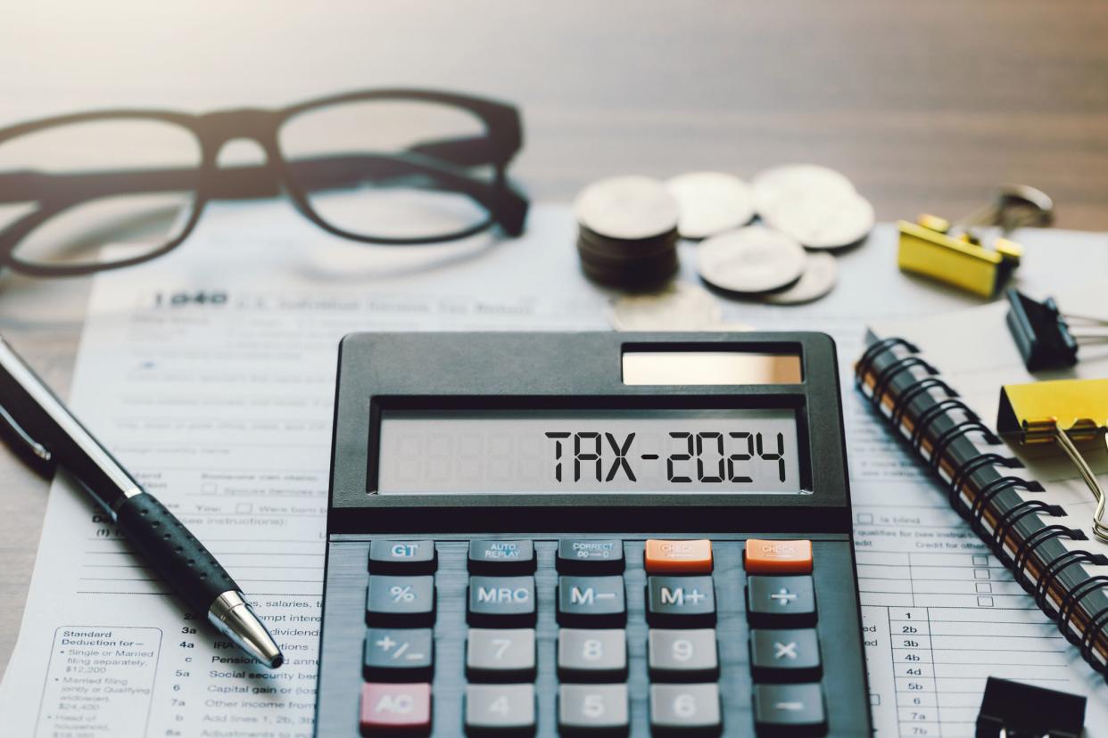 Word Tax 2024 on the calculator. Business and tax concept.Calculator, coins, book, tax form, and pen on table.Tax deduction planning.Financial research, government taxes, and calculation tax return