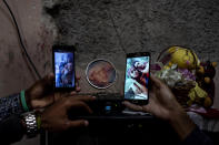Relatives show photos of the three Roman siblings who are in prison accused of participating in anti-government protests, at their home in the La Guinera neighborhood of Havana, Cuba, Wednesday, Jan. 19, 2022. Six months after surprising protests against the Cuban government, more than 50 protesters charged with sedition are headed to trial and could face prison sentences up to 30 years. (AP Photo/Ramon Espinosa)