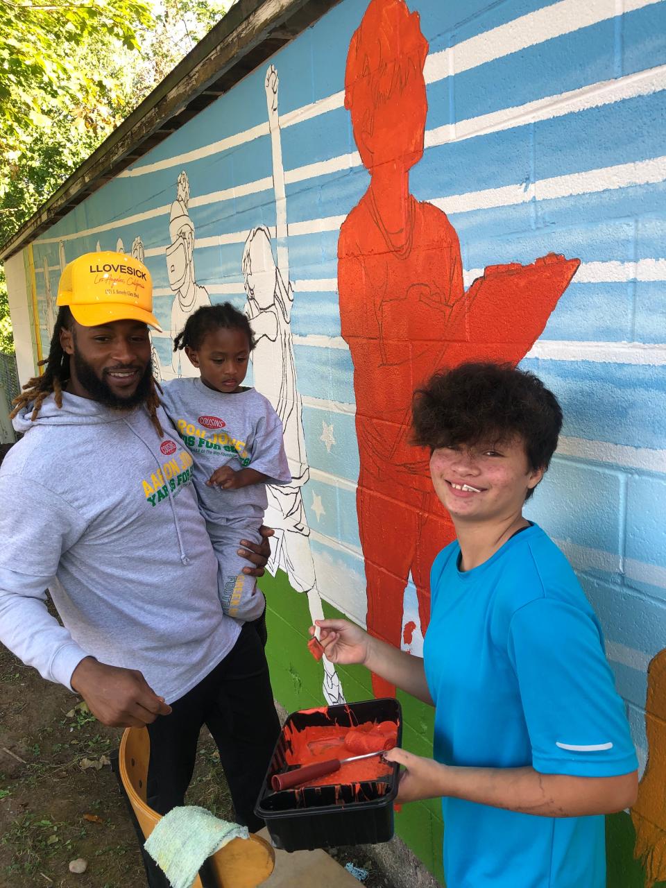 Packers' running back Aaron Jones helps paint a mural with his son and club member Jade Giesler, 13, at the Boys and Girls Club of Greater Green Bay Nagel Unit-West Side Clubhouse during the summer of 2022 in Green Bay, Wisconsin.