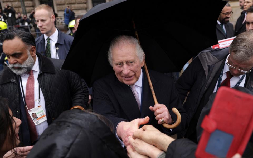 The King meets with people in the crowd during a walkabout while sheltering from the rain - Sean Gallup/Getty Images Europe