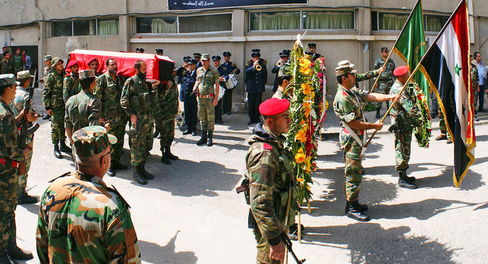 In this Monday, March 24, 2014 photo released by the Syrian official news agency SANA, Syrian soldiers carry the coffin of the commander of the pro-government National Defense Forces Hilal Assad, during his funeral at a hospital in Latakia province, Syria. State TV reported late Sunday that Hilal Assad was killed in the fighting against opposition fighters in Kassab. The commander was a member of Syrian President Bashar Assad's family but the TV did not say if they were close relatives. (AP Photo/SANA)