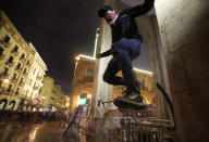 An anti-government protester jumps from barriers after he throws stones against the riot police, during ongoing protests against the political elites who have ruled the country since decades, in Beirut, Lebanon, Sunday, Jan. 19, 2020. (AP Photo/Hassan Ammar)