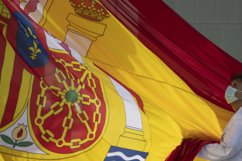 Dr. Miguel Angel Gonzalez Gallego holds a Spanish flag during a memorial for coronavirus (COVID-19) victims in Madrid, Spain, Friday, Oct. 23, 2020. Spanish Prime Minster Pedro Sanchez is appealing for Spaniards to pull together and defeat the new coronavirus, warning: "The situation is serious". (AP Photo/Manu Fernandez)