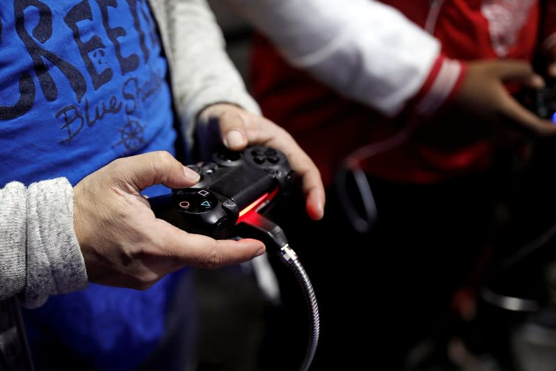 FILE PHOTO: Visitors play games on PlayStation 4 (PS4) at the Paris Games Week, a trade fair for video games in Paris