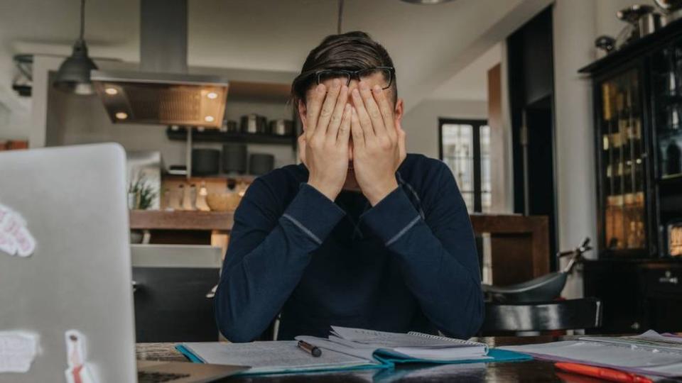 Persona frente al computador con el rostro entre sus manos