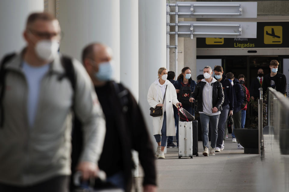 Passengers wearing face masks arrive at Palma de Mallorca Airport on the Spanish Balearic Island of Mallorca, Spain, Saturday, March 27, 2021. Efforts in Spain to restart tourism activity is drawing a mixed picture due to a patchwork of national, regional and European rules on travel that is confusing both tourists and their hosts. (AP Photo/Francisco Ubilla)