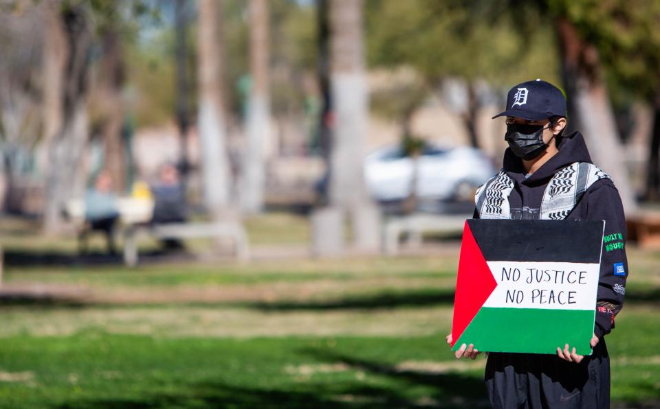 Ezra Rizo holds up a sign and watches from a distance during a rally hosted by the Palestinian American Community Center outside the Arizona state Capitol in Phoenix on Jan. 8, 2024.