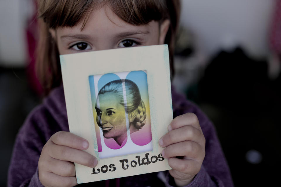 Lariza Monia holds a drawing of Eva Peron at a fair in Los Toldos, Argentina, Monday, May 6, 2019. One day ahead of the 100th anniversary of Evita's birth, the home where Argentina's mythical first lady was born and raised was opened to the public with an exhibition recounting the childhood of the woman who, together with her husband Juan Domingo Perón, will forever mark Argentine history. (AP Photo/Natacha Pisarenko)
