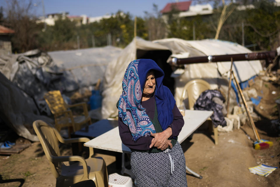 FILE - An elderly woman stands next to greenhouses where she shelters with her relatives following the earthquake in Samandag, southern Turkey, on Feb. 16, 2023. Hundreds of thousands of people are seeking shelter after the Feb. 6 earthquake in southern Turkey left homes unlivable. Many survivors have been unable to find tents or containers dispatched to the region by the government and aid agencies, Instead they have sought refuge in any structure that can protect them from the winter conditions, including greenhouses, rail carriages and factories. (AP Photo/Francisco Seco)