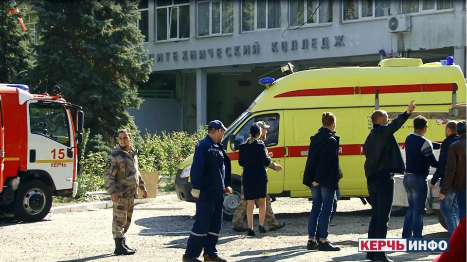 RETRANSMISSION TO CORRECT TO SHOOTING NOT EXPLOSION - Policemen, medics and investigators stand near the vocational college, in Kerch, Crimea, Wednesday Oct. 17, 2018. An 18-year-old student strode into his vocational school in Crimea, a hoodie covering his blond hair, then pulled out a shotgun and opened fire on Wednesday, killing 19 students and wounding more than 50 others before killing himself. (Kerch Info News via AP)