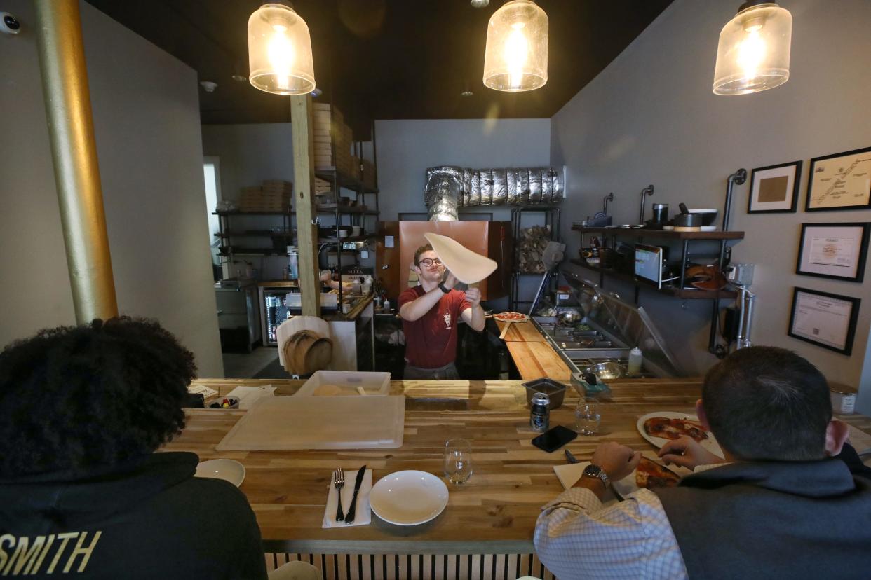 Owner and chef Kody Derhak tosses dough as he creates another pizza as patrons watch from the 'pizza bar' counter during the lunch-hour rush at the newly opened Ardor Park artisanal pizza on Park Avenue in Rochester Thursday, April 4, 2024.