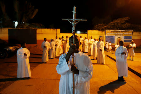 An altar boy holds a cross before the Christmas Eve mass at the Notre Dame de Kinshasa cathedral in Kinshasa, Democratic Republic of Congo, December 24, 2018. REUTERS/Baz Ratner