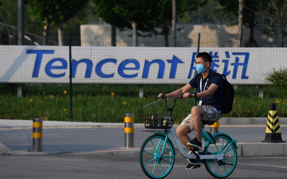 A man cycles past the Beijing headquarters for Tencent, the parent company of WeChat, one of two Chinese social media giants faces a ban after President Trump's move  - Greg Baker/AFP