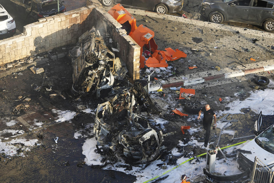 Soldados israelíes sofocan un incendio provocado por el impacto de un proyectil disparado desde la Franja de Gaza en un estacionamiento en Ashkelon, en el sur de Israel, el 7 de octubre de 2023. (AP Foto/Tsafrir Abayov)