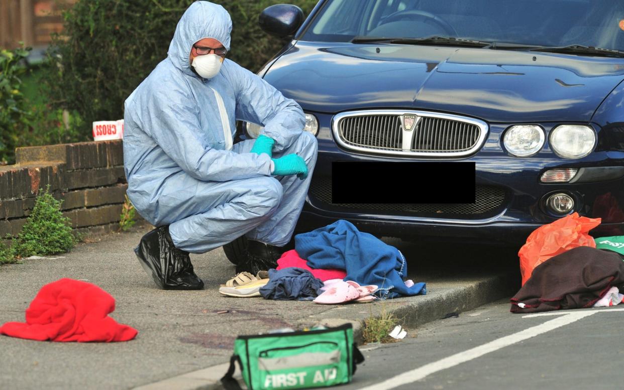 A police forensics officer stands over blood-stained clothing at the scene of the hammer attack in Eltham, south-east London - London News Pictures Ltd