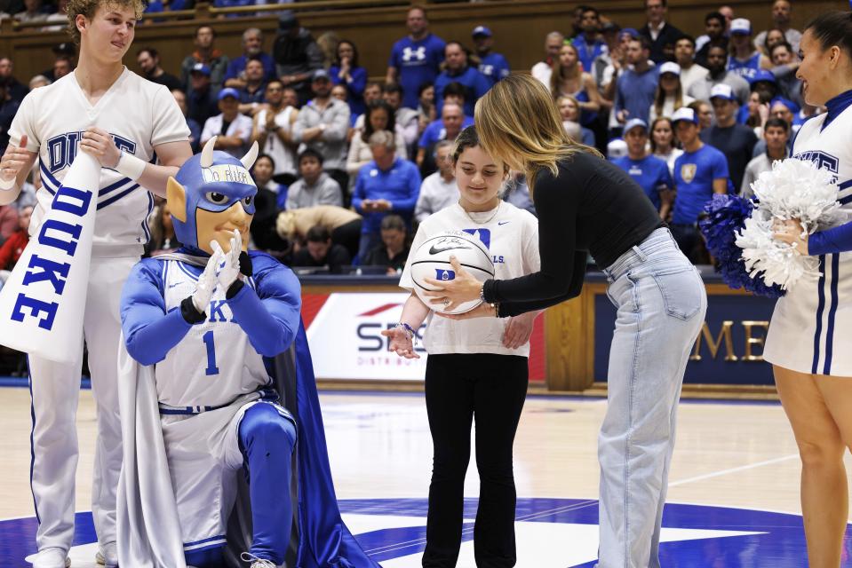 Marcelle Scheyer, right, presents a basketball to Samantha DiMartino, as an honoree of the Scheyer Family Kid Captain Program, which recognizes patients and families of Duke Children's Hospital, during a timeout in an NCAA college basketball game between Duke and Louisville in Durham, N.C., Wednesday, Feb. 28, 2024. (AP Photo/Ben McKeown)