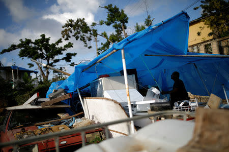 Joe Quirindongo tries to repair a makeshift tent where he keeps some belongings at the squatter community of Villa Hugo in Canovanas, Puerto Rico, December 9, 2017. REUTERS/Carlos Garcia Rawlins