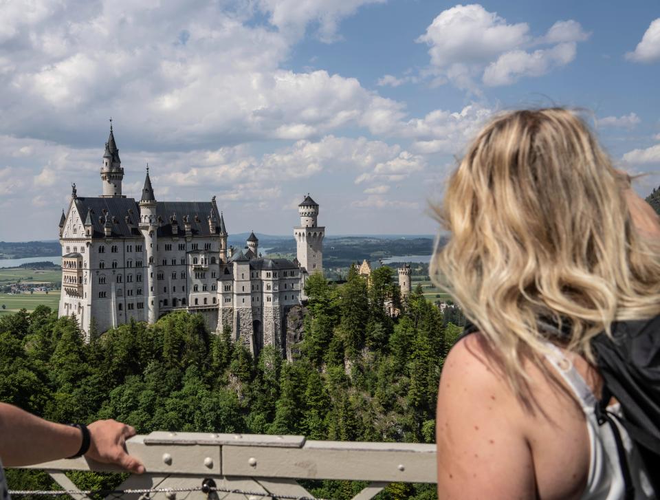 People watch the Neuschwanstein castle, in Schwangau, Germany, Thursday, June 15, 2023. Authorities say an American man has been arrested in Germany after allegedly assaulting two tourists he met near Neuschwanstein castle. The attack, which occurred on Wednesday, left one of the women dead. Police said Thursday that the 30-year-old man met the two women on a hiking path and lured them onto a trail. They said the man then “physically attacked” the younger woman. (Frank Rumpenhorst/dpa via AP) ORG XMIT: SCH803