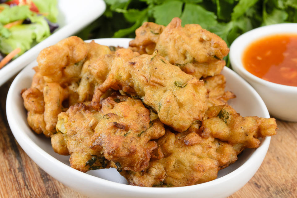 Vegetable pakora or onion bhaji served with salad and chili sauce.