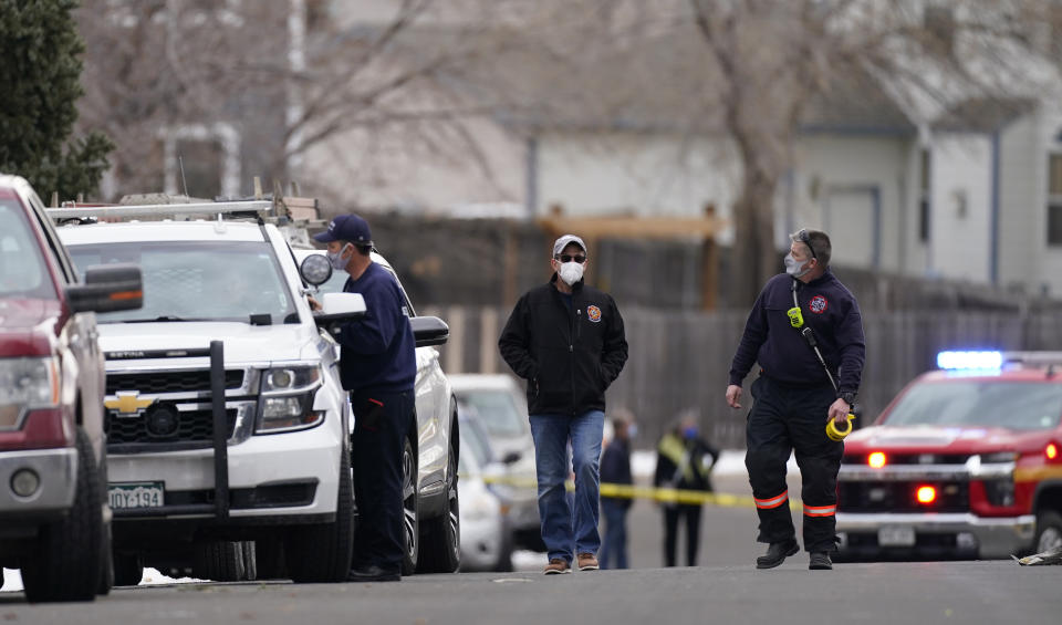 Fire officials walk up Elmwood Street to see where a piece of debris from a passenger airplane crushed a pickup truck parked next to a home in Broomfield, Colo., as the plane shed parts while making an emergency landing at nearby Denver International Airport Saturday, Feb. 20, 2021. (AP Photo/David Zalubowski)