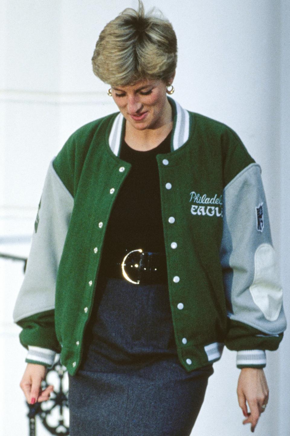 Diana, Princess of Wales (1961 - 1997) wearing a Philadelphia Eagles jacket to drop off her son Prince Harry at Wetherby School in London, January 1991. Prince William (left) is leaving with her, accompanied by a friend.