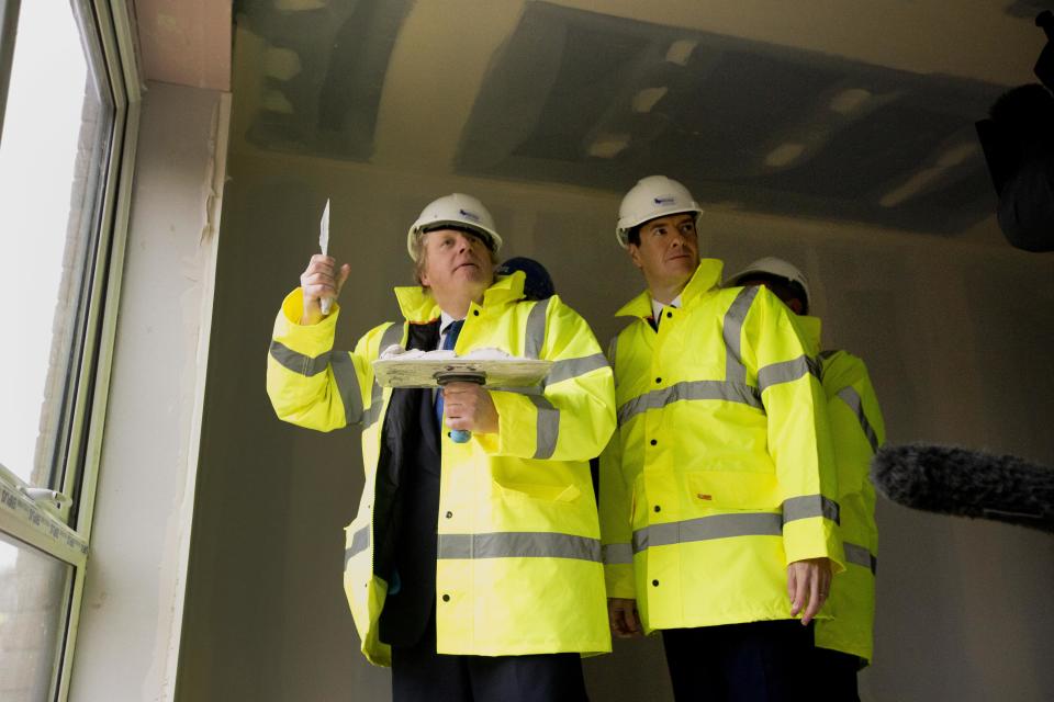 After a short demonstration on plastering, Britain's Chancellor of the Exchequer George Osborne, centre right, and London mayor Boris Johnson make an attempt to plaster, during their visit to the Aura residential development which is under construction, in the Edgware district, of north London, Friday, Feb. 20, 2015.  Osborne and Johnson earlier on Friday announced plans to identify public sector sites in London for future housing developments and to increase 24-hour rail services across more underground tube lines, the London Overground trains and the London Docklands Light Railway in coming years. (AP Photo/Matt Dunham, Pool)