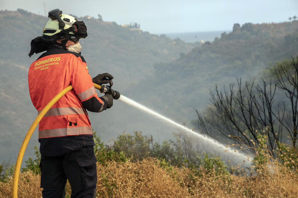 A forest firefighter works in a wildfire in Estepona, Spain, Thursday, Sept. 9, 2021. Nearly 800 people have been evacuated from their homes and road traffic has been disrupted as firefighting teams and planes fight a wildfire in southwestern Spain. (AP Photo/Sergio Rodrigo)