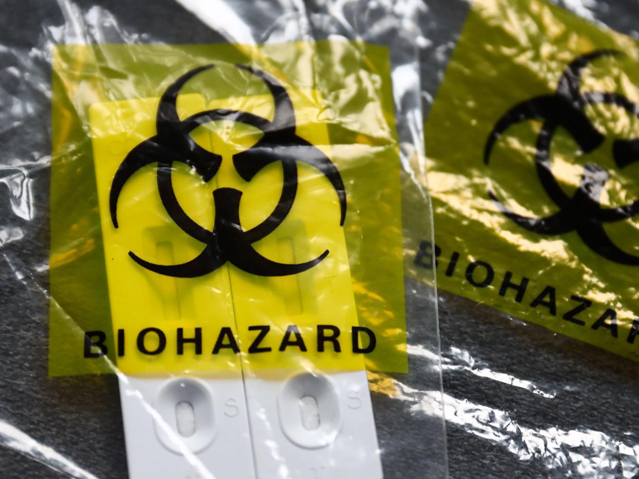 COVID-19 rapid antigen tests and plastic bags with 'biohazard' signs are seen in this illustration photo taken in Krakow, Poland on January 31, 2023.