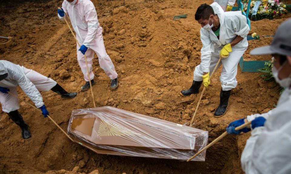 Workers lower the coffin of a Covid victim in Brazil