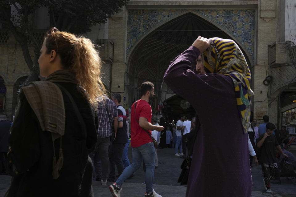 Two women walk at the old main bazaar of Tehran, as one of them without covering her mandatory Islamic headscarf, Iran, Saturday, Oct. 1, 2022. Thousands of Iranians have taken to the streets over the last two weeks to protest the death of Mahsa Amini, a 22-year-old woman who had been detained by the morality police in the capital of Tehran for allegedly wearing her mandatory Islamic veil too loosely. (AP Photo/Vahid Salemi)