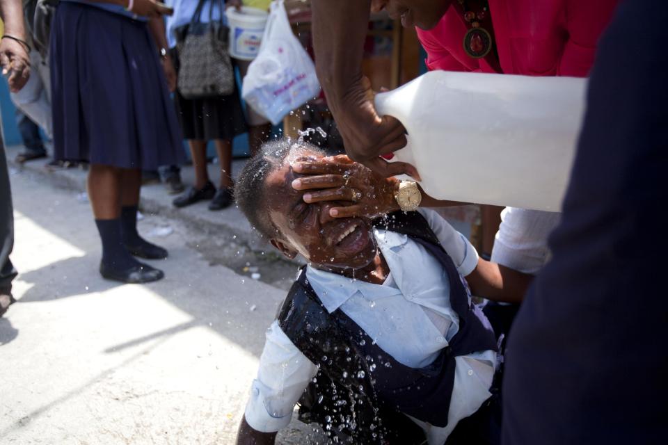 A student affected by tear gas is helped during clashes between students and the national police in Port-au-Prince, Haiti, Wednesday, May 7, 2014. Students are protesting to demand authorities respond to their striking teachers' demands for higher pay and improved working conditions. Students are concerned they will not be able to take exams which allow them to move on to the next level. Public school teachers across Haiti have been on strike for one week. (AP Photo/Dieu Nalio Chery)