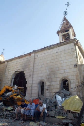 Iraqis sit outside the Holy Family church in the north of Kirkuk on August 2, 2011, after a car bomb exploded and injured 15 people including church staff