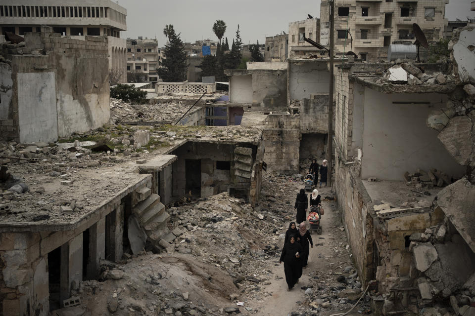 FILE - In this March 12, 2020 file photo, women walk in a neighborhood heavily damaged by airstrikes in Idlib, Syria. Hundreds of thousands of Syrians face continued displacement each coming year if the conflict continues and economic conditions further deteriorate, the Norwegian Refugee Council, a prominent humanitarian organization said Monday, March 8, 2021. The Syrian conflict, which marks 10 years later this month, has resulted in the largest displacement crisis since World War II, with an estimated 2.4 million people displaced in and outside Syria every year since the war begin in 2011, the council said. (AP Photo/Felipe Dana, File)