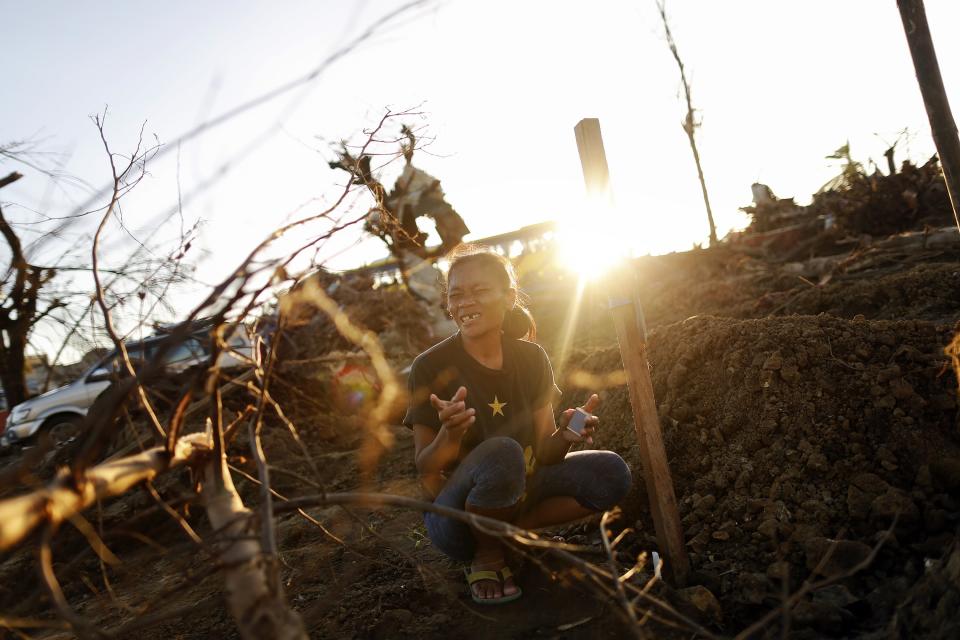 Marilou Cassanares cries as she lights a candle by a mass grave where her husband was buried in Palo