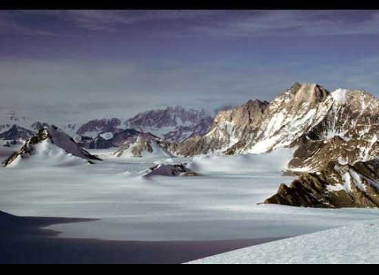 Grizzly Peak and Mt. Zanuck  tower over the northern (right) flank of Sanctuary Glacier.  The Hays Mountains merge into cloud on the far side of Scott Glacier, glimpsed flowing left to right in the gap between the low peaks in the left center of the image.