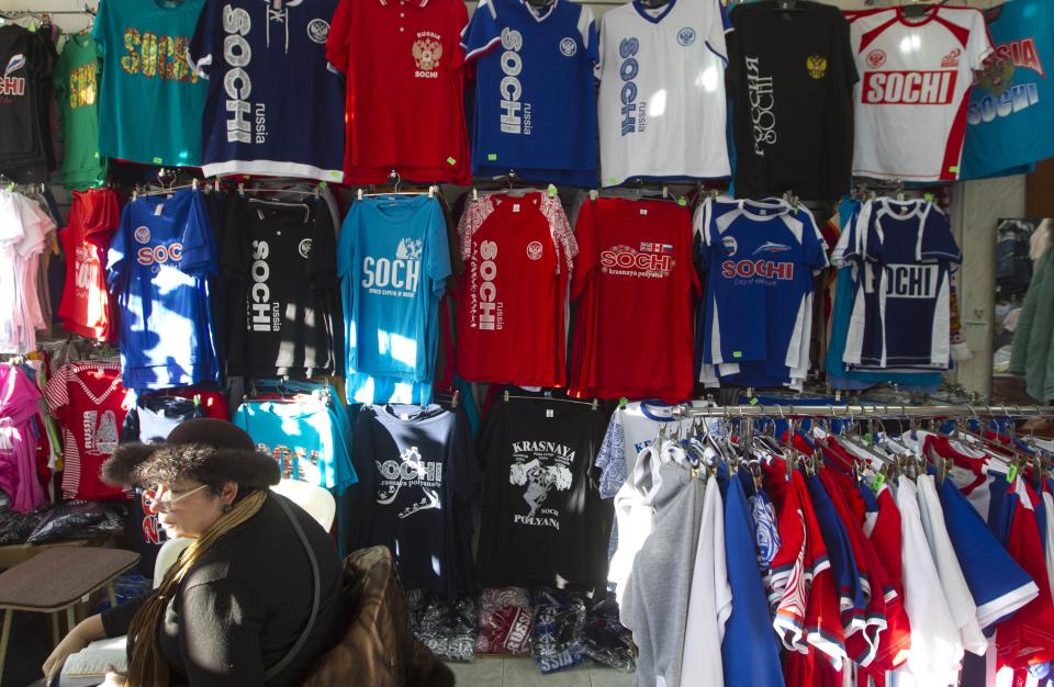 A woman sits in front of a shop selling souvenir t-shirts in Sochi December 30, 2013. The International Olympic Committee has no doubt Russian authorities will be able to provide security at the Winter Olympics, a spokeswoman said on Monday after two bomb blasts killed tens of people in the Russian city of Volgograd. REUTERS/Maxim Shemetov (RUSSIA - Tags: SPORT OLYMPICS CRIME LAW DISASTER)