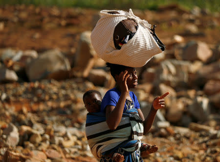 A survivor of Cyclone Idai carries her baby as she moves to higher ground at Ngangu suburb in Chimanimani, Zimbabwe, March 22, 2019. REUTERS/Philimon Bulawayo